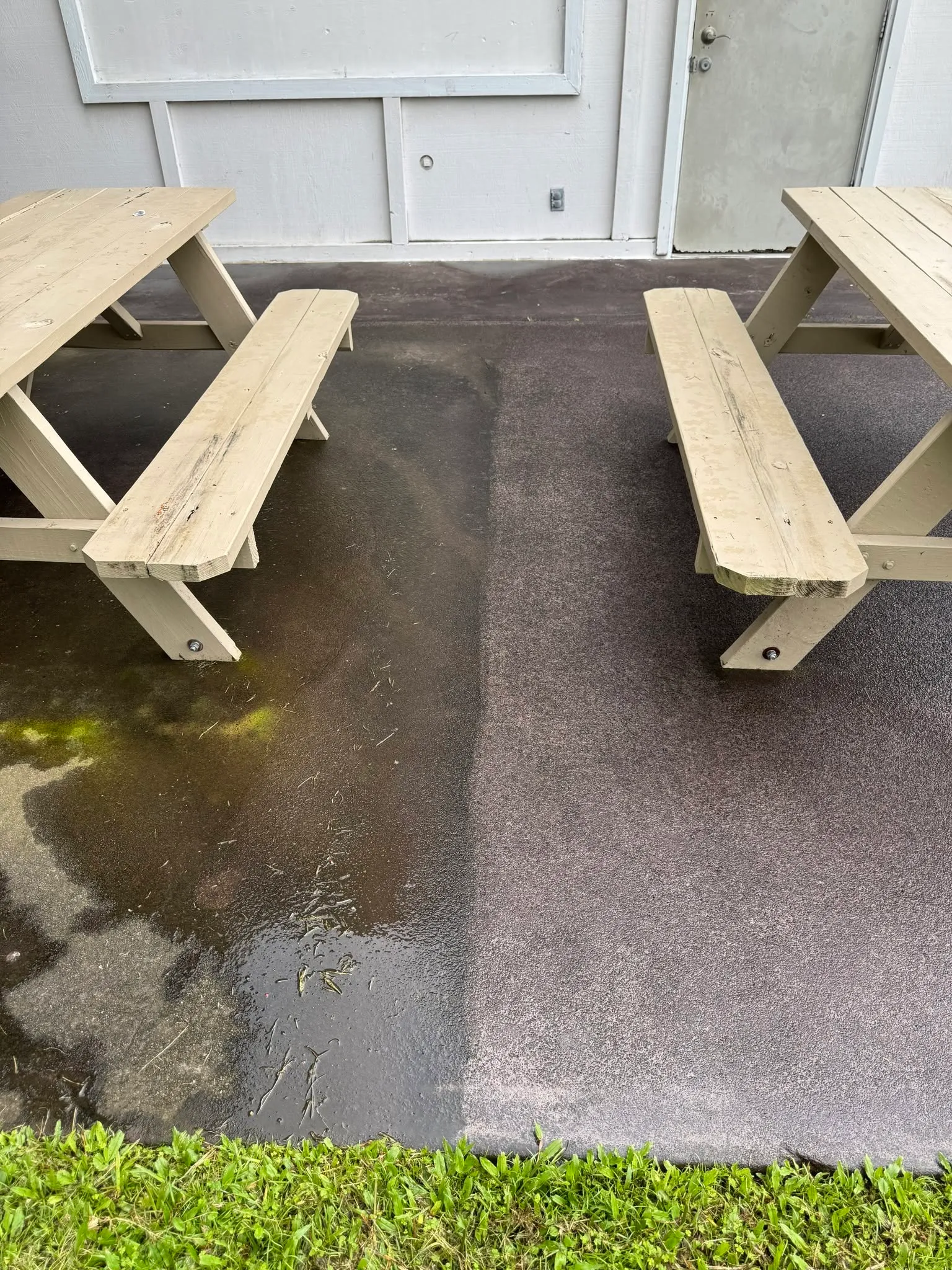 Side-by-side before and after of a paved outdoor area with two picnic tables. The left half is dark and stained with patches of green growth; the right half is clean and even.